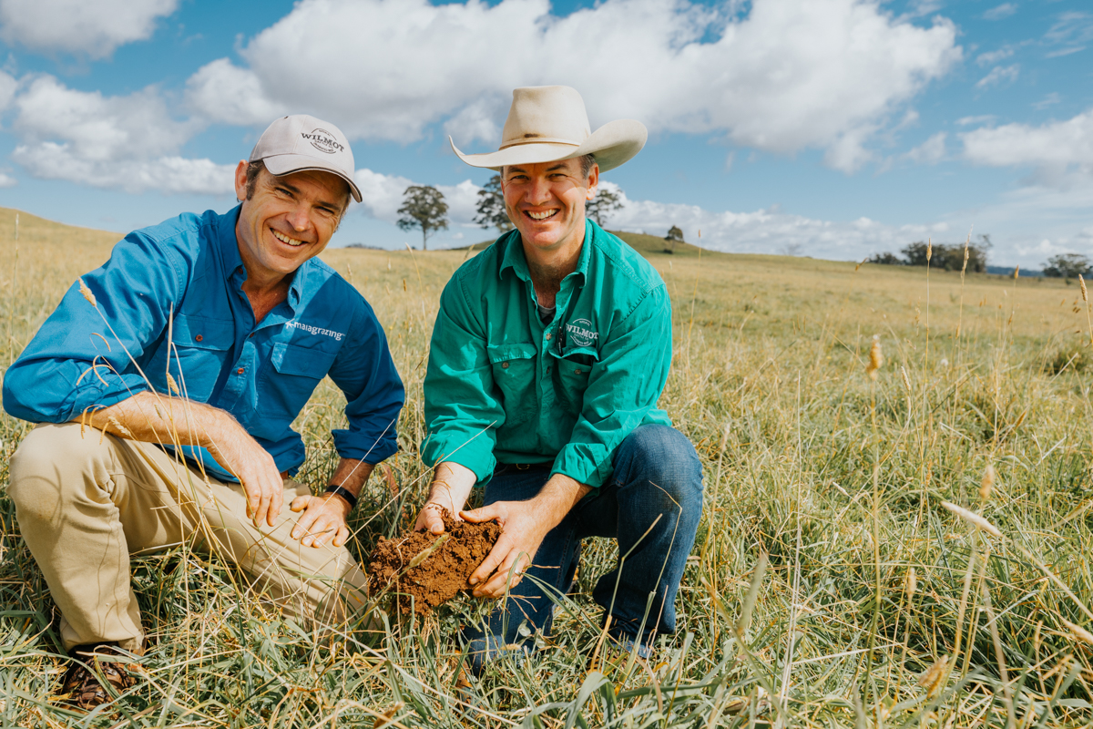 Two farmers in a field with some soil in their hands.